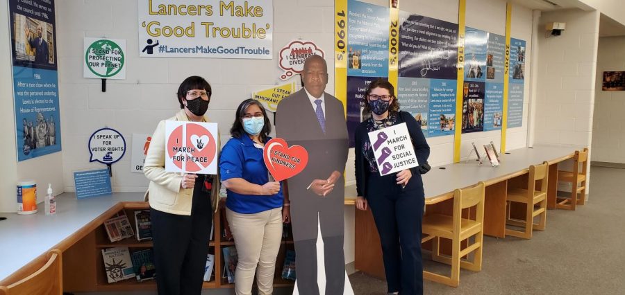 Library staff Mimi Marquet, Lourdes Salas, and Lisa Koch pose in front of a paper cut-out of Rep. John Lewis during the John R. Lewis High School Rededication Ceremony, April 23, 2021.